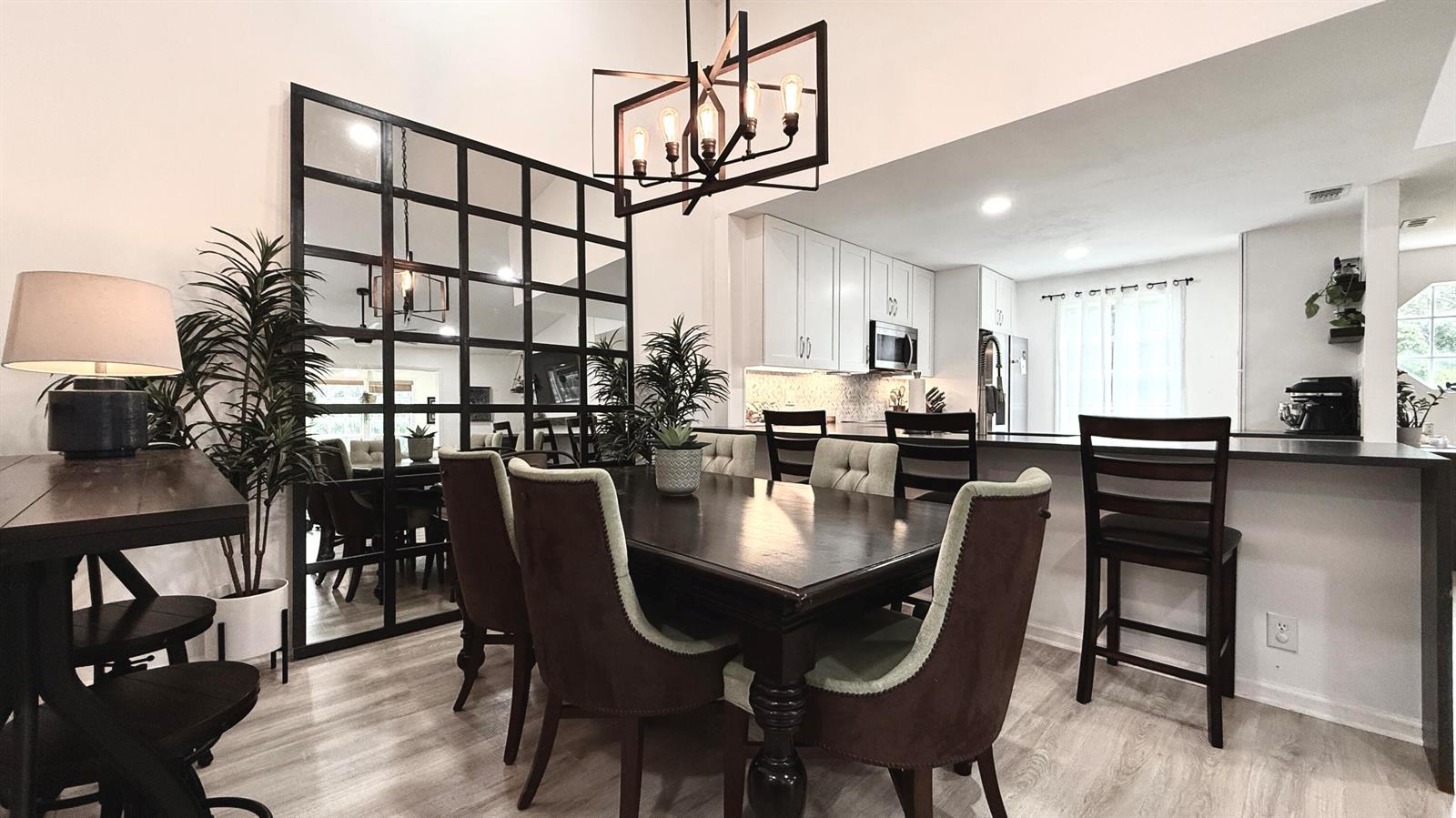 A dining area features a dark wood table, upholstered chairs, and a large grid mirror — 5016 Heatherhill Lane # 10, Boca Raton FL 33486, BOCA RATON, FL