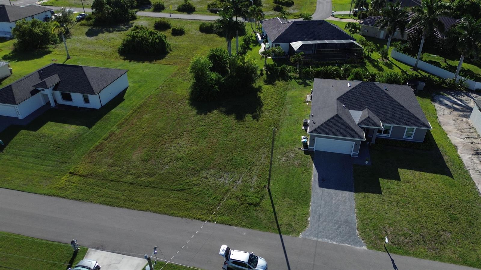 An aerial view shows a vacant residential lot situated between two single-family homes — 2012 NW 24th Place, Cape Coral FL 33993, CAPE CORAL, FL
