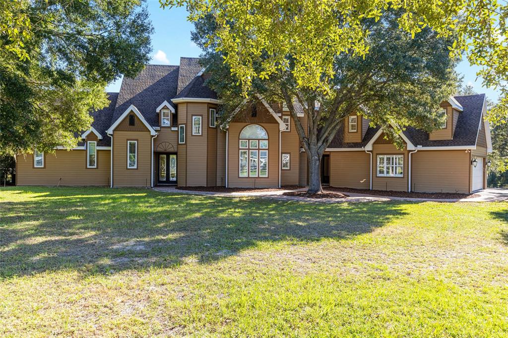 A large, two-story brown house with a shingled roof and a spacious front lawn — 997 NW 63RD COURT, OCALA, FL