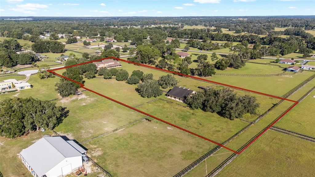 An aerial view shows a fenced rural property with a house, barn, and pasture land — 997 NW 63RD COURT, OCALA, FL