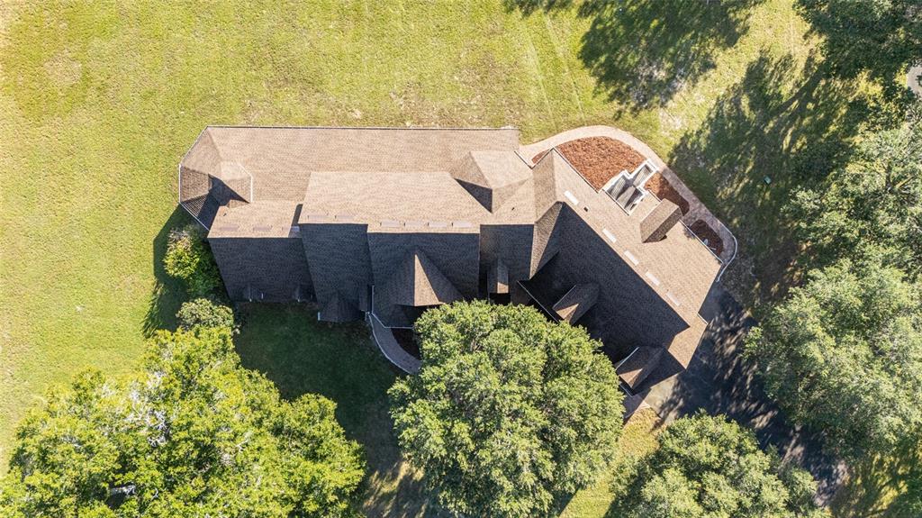 An aerial view shows a large house with a complex shingled roof surrounded by trees — 997 NW 63RD COURT, OCALA, FL