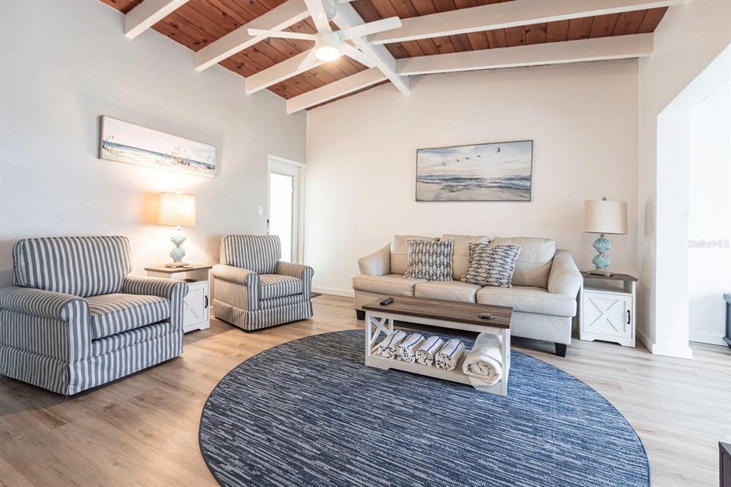 A living room features a vaulted wood-paneled ceiling, striped armchairs, a sofa, and a rug — 6006 MIDNIGHT PASS ROAD UNIT 54, SARASOTA, FL