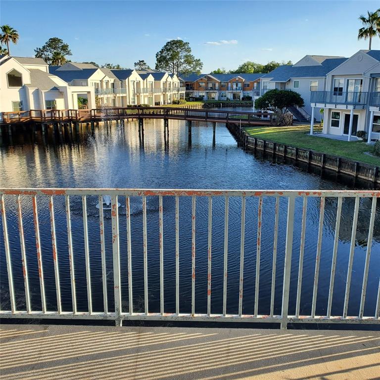 A view of a pond with a fountain and a wooden footbridge between apartment buildings — 2504 WOODGATE BOULEVARD UNIT 205, ORLANDO, FL