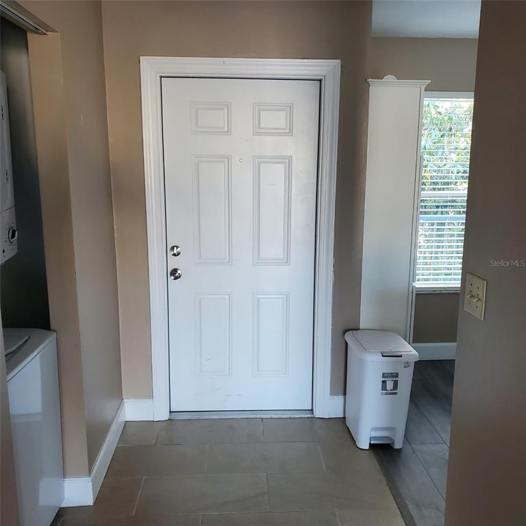 A white door with two locks stands in a tiled entryway next to a trash can — 2504 WOODGATE BOULEVARD UNIT 205, ORLANDO, FL
