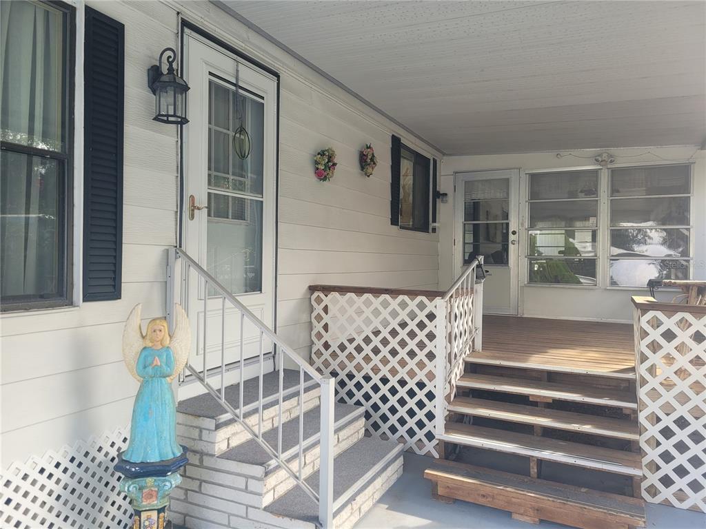 A covered porch features two sets of stairs, white lattice railings, and a blue angel statue — 3027 GALAXY LANE, LAKELAND, FL
