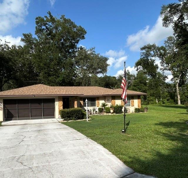 A single-story house with a brown shingled roof, garage, and an American flag in front — 10335 N ABBY DRIVE, CITRUS SPRINGS, FL