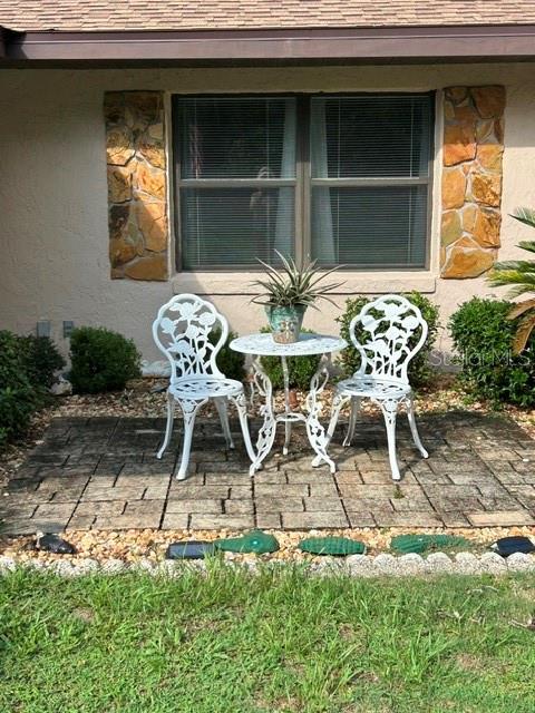 A small patio with a metal bistro set sits in front of a house window — 10335 N ABBY DRIVE, CITRUS SPRINGS, FL