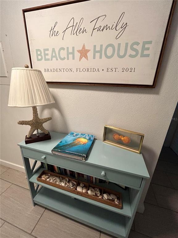 A light blue console table sits beneath a beach-themed sign on a white wall — 6301 MANATEE AVENUE W, BRADENTON, FL