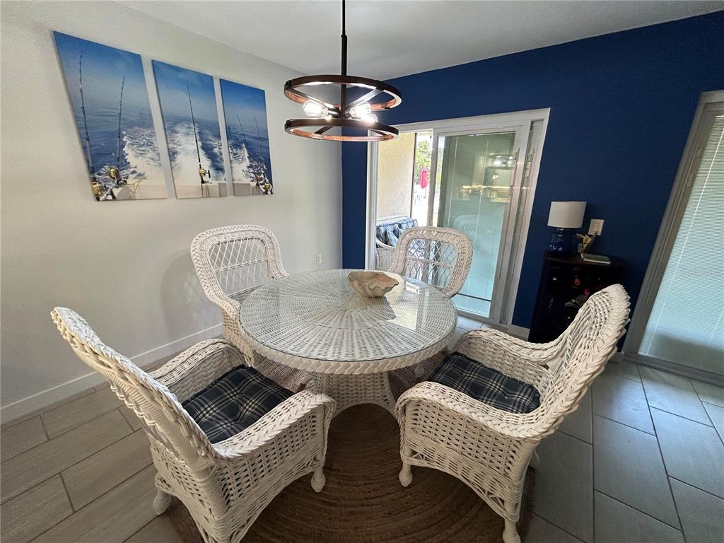 A dining area features a round glass-topped wicker table, four wicker chairs, and blue walls — 6301 MANATEE AVENUE W, BRADENTON, FL