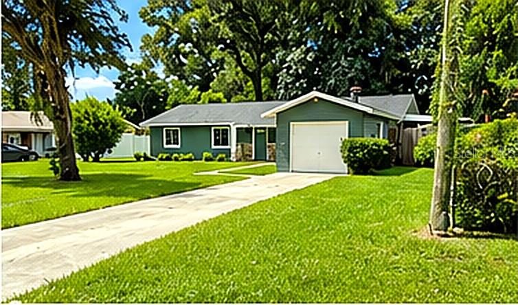 A green single-story house with a white garage door and a concrete driveway — 1415 NE 53RD STREET, OCALA, FL