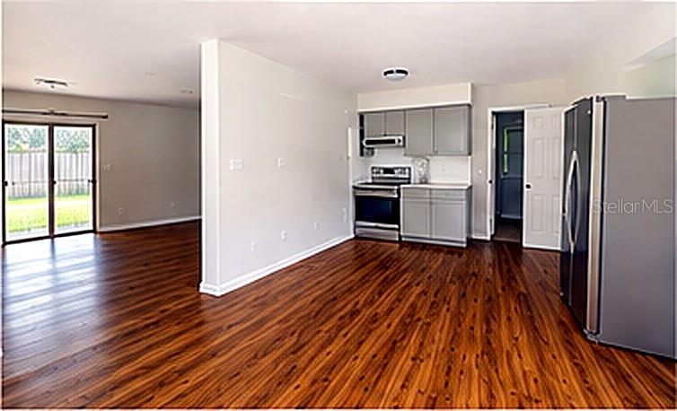 An open-concept kitchen and living area feature wood-look flooring, gray cabinets, and stainless steel appliances — 1415 NE 53RD STREET, OCALA, FL