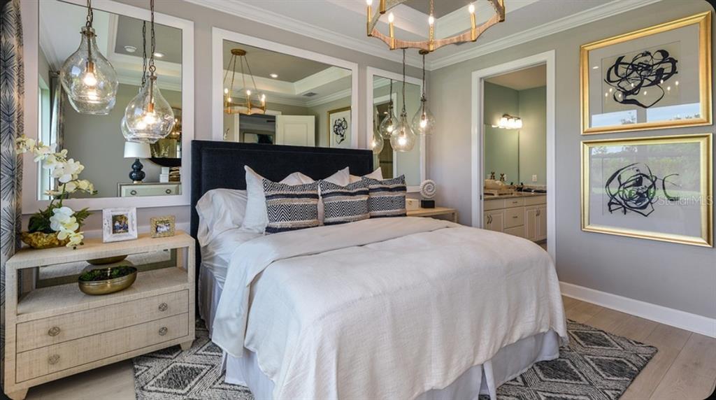 A bedroom features a dark upholstered headboard, mirrored wall panels, pendant lighting, and two framed artworks — 14517 DERNA TERRACE, BRADENTON, FL