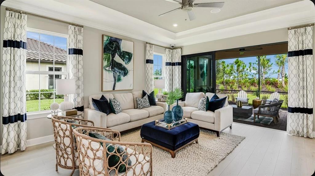 A living room features a beige sofa, blue ottoman, and sliding glass doors to a patio — 14517 DERNA TERRACE, BRADENTON, FL