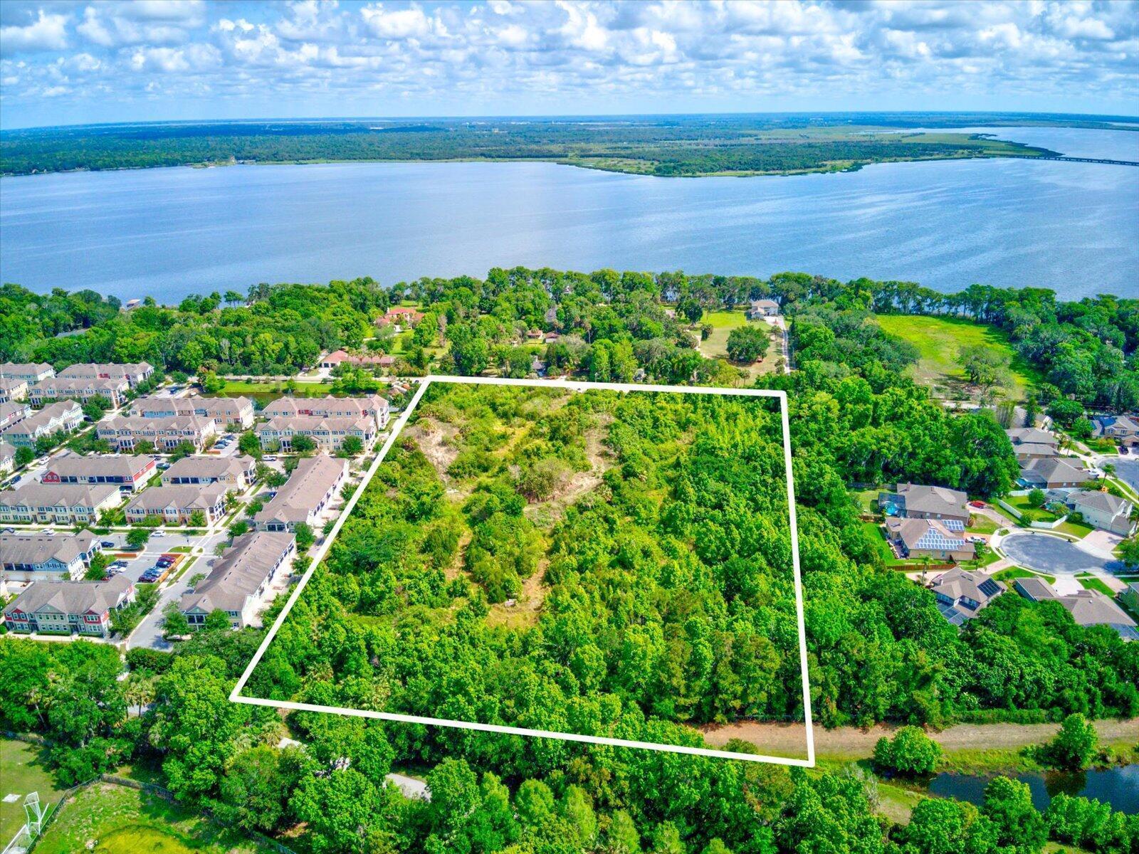 An aerial view shows a rectangular plot of undeveloped land surrounded by trees and houses — 1205 Orange Avenue, FL 32708, FL