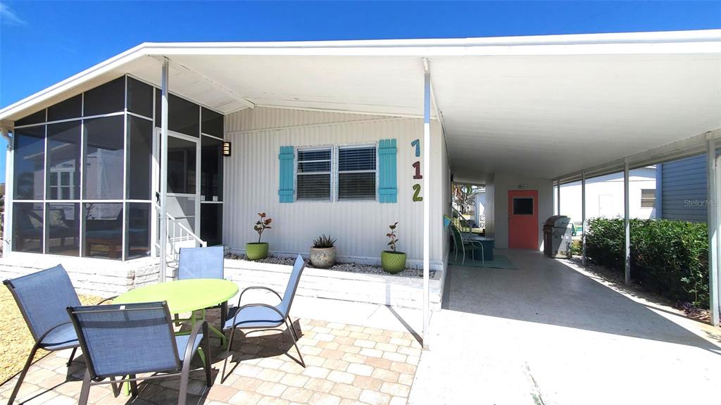 A mobile home exterior features a screened porch, a paved patio, and a covered carport — 712 CAREFREE, VENICE, FL