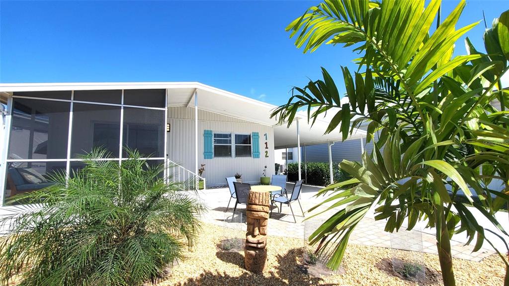 A mobile home exterior features a screened porch, a carport, and a small patio area — 712 CAREFREE, VENICE, FL