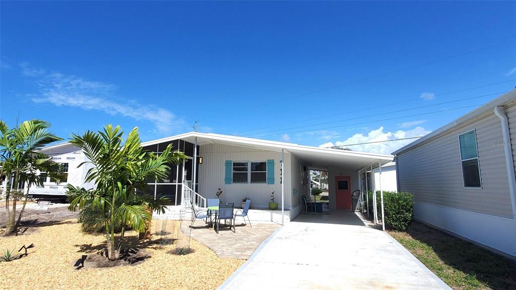 A single-story manufactured home with a carport, a paved patio, and a screened-in porch — 712 CAREFREE, VENICE, FL