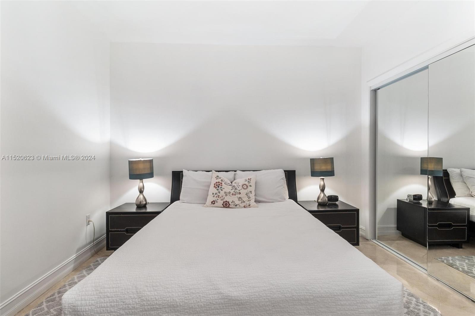 A bedroom features a bed with two nightstands, matching lamps, and a mirrored closet door — 1830 S Ocean Dr # 3809, Hallandale Beach FL 33009, HALLANDALE BEACH, FL
