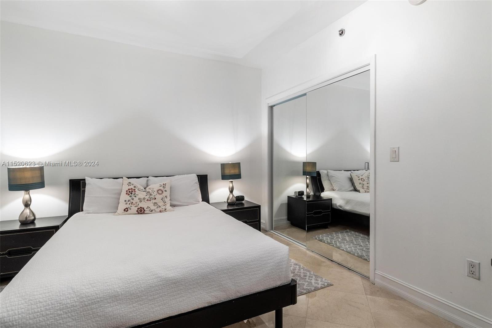 A bedroom features a bed with a white quilt, two nightstands, and mirrored closet doors — 1830 S Ocean Dr # 3809, Hallandale Beach FL 33009, HALLANDALE BEACH, FL