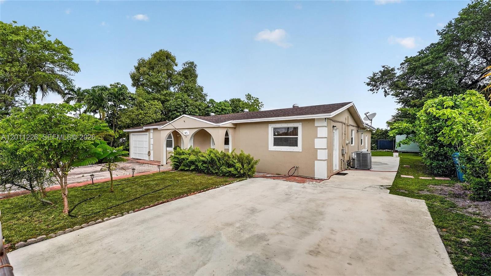 A single-story house with a beige exterior, a concrete driveway, and a small front lawn — 4271 NW 192nd St, Miami Gardens FL 33055, MIAMI GARDENS, FL