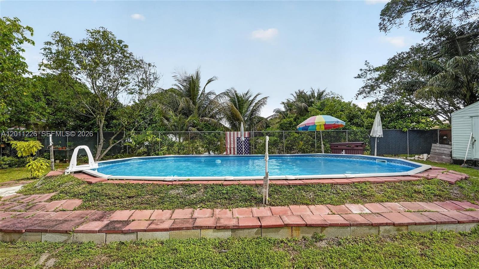 An above-ground swimming pool sits in a grassy backyard enclosed by a chain-link fence — 4271 NW 192nd St, Miami Gardens FL 33055, MIAMI GARDENS, FL