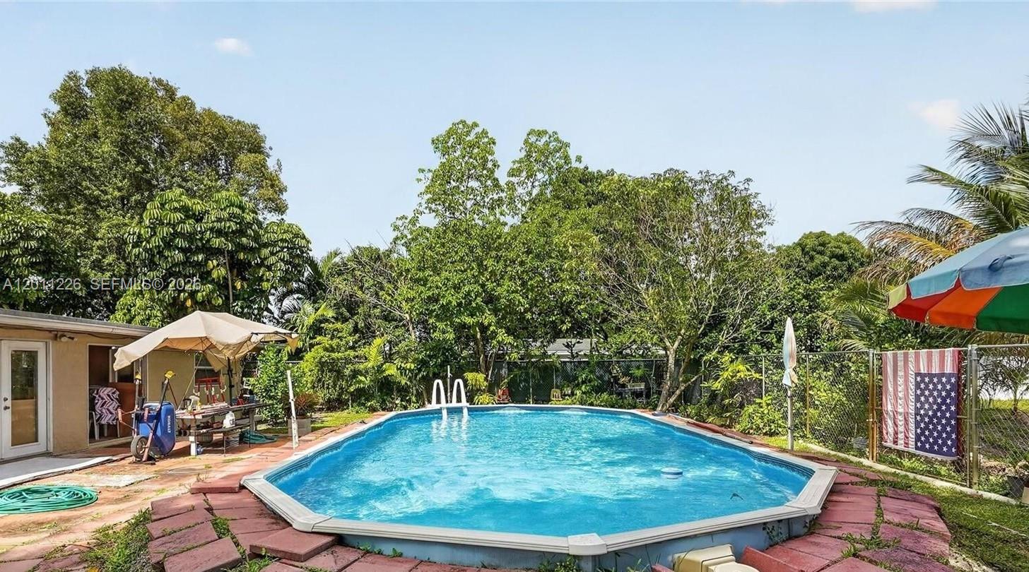 An above-ground swimming pool sits on a red brick patio in a grassy backyard — 4271 NW 192nd St, Miami Gardens FL 33055, MIAMI GARDENS, FL