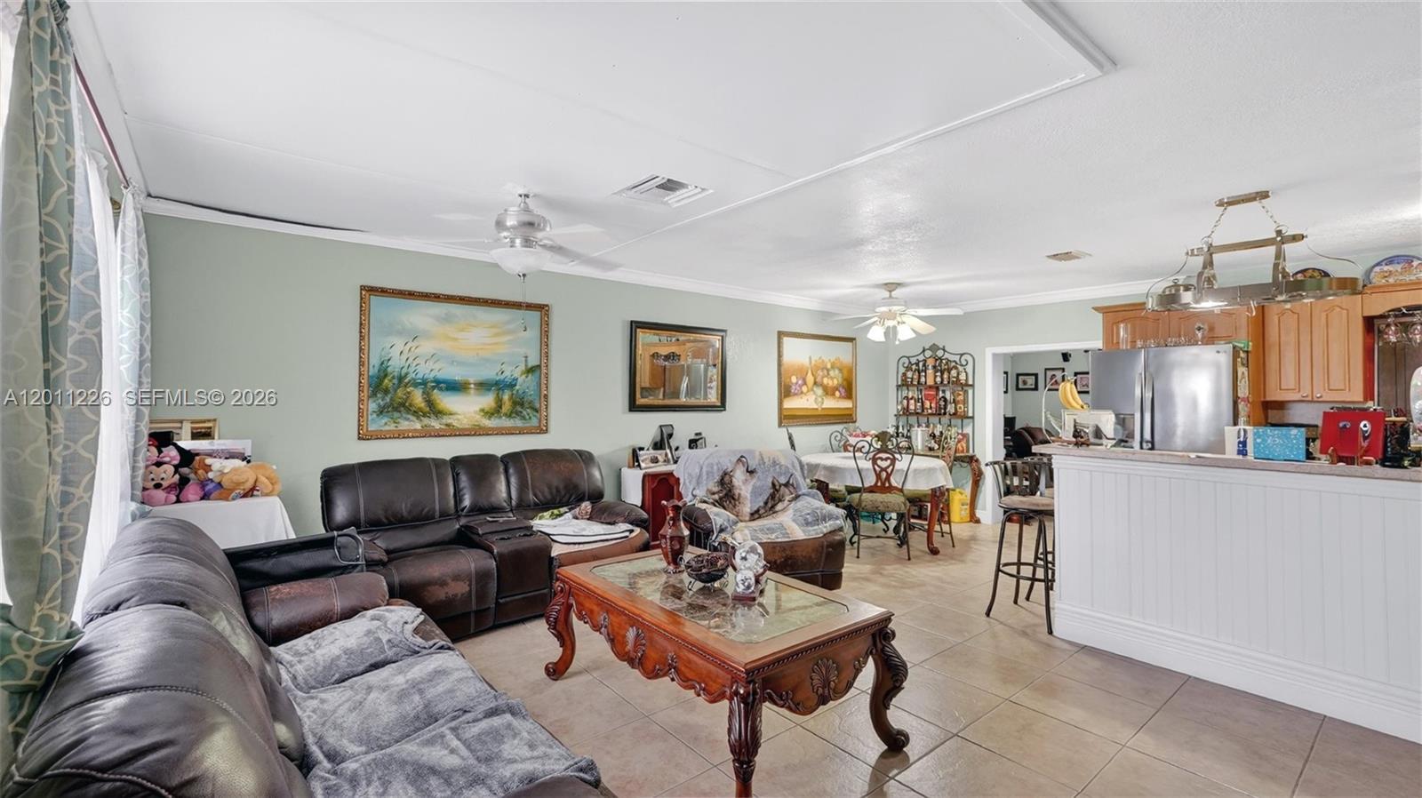 A living room and kitchen area features tile flooring, leather furniture, and a wooden coffee table — 4271 NW 192nd St, Miami Gardens FL 33055, MIAMI GARDENS, FL