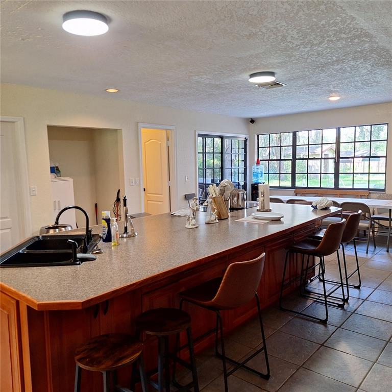 A kitchen features a large island with a sink, bar seating, and wooden cabinetry — 10012 LAKE LOUISA ROAD, CLERMONT, FL