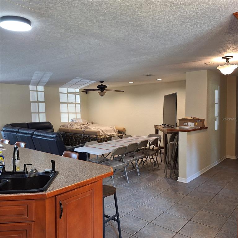 A kitchen island overlooks a living area with a dining table and sofa — 10012 LAKE LOUISA ROAD, CLERMONT, FL