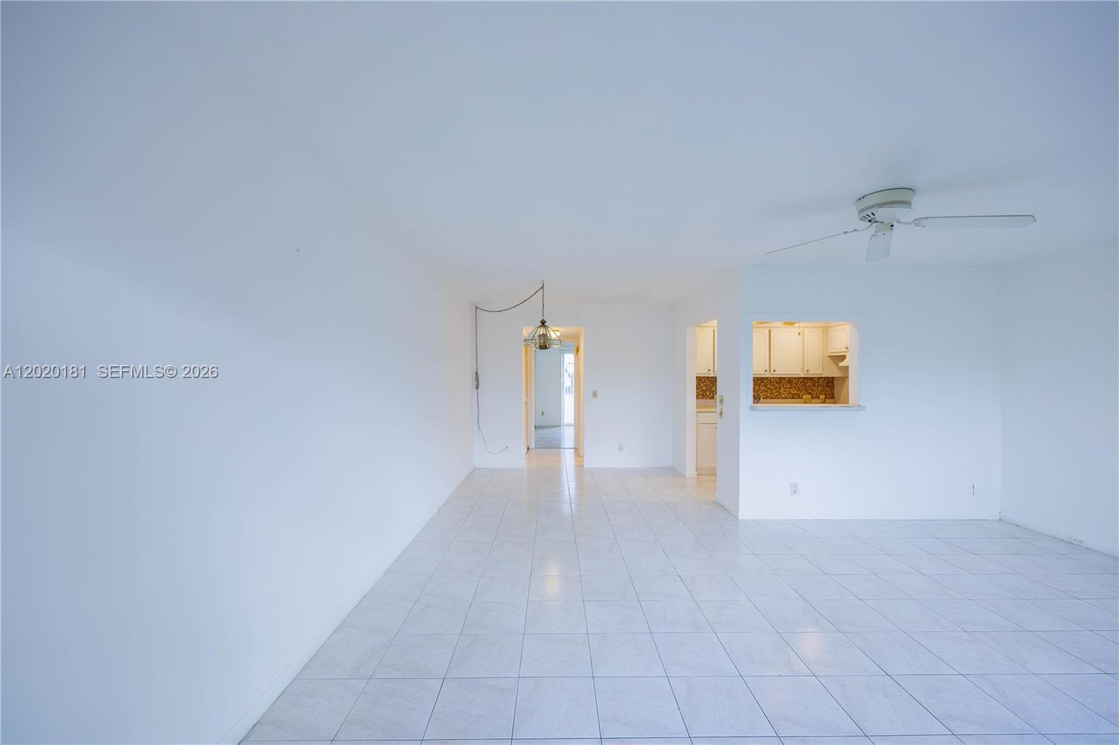A bright, empty room features white walls, tiled floors, a ceiling fan, and a pass-through window — 303 Preston H # 303, Boca Raton FL 33434, BOCA RATON, FL