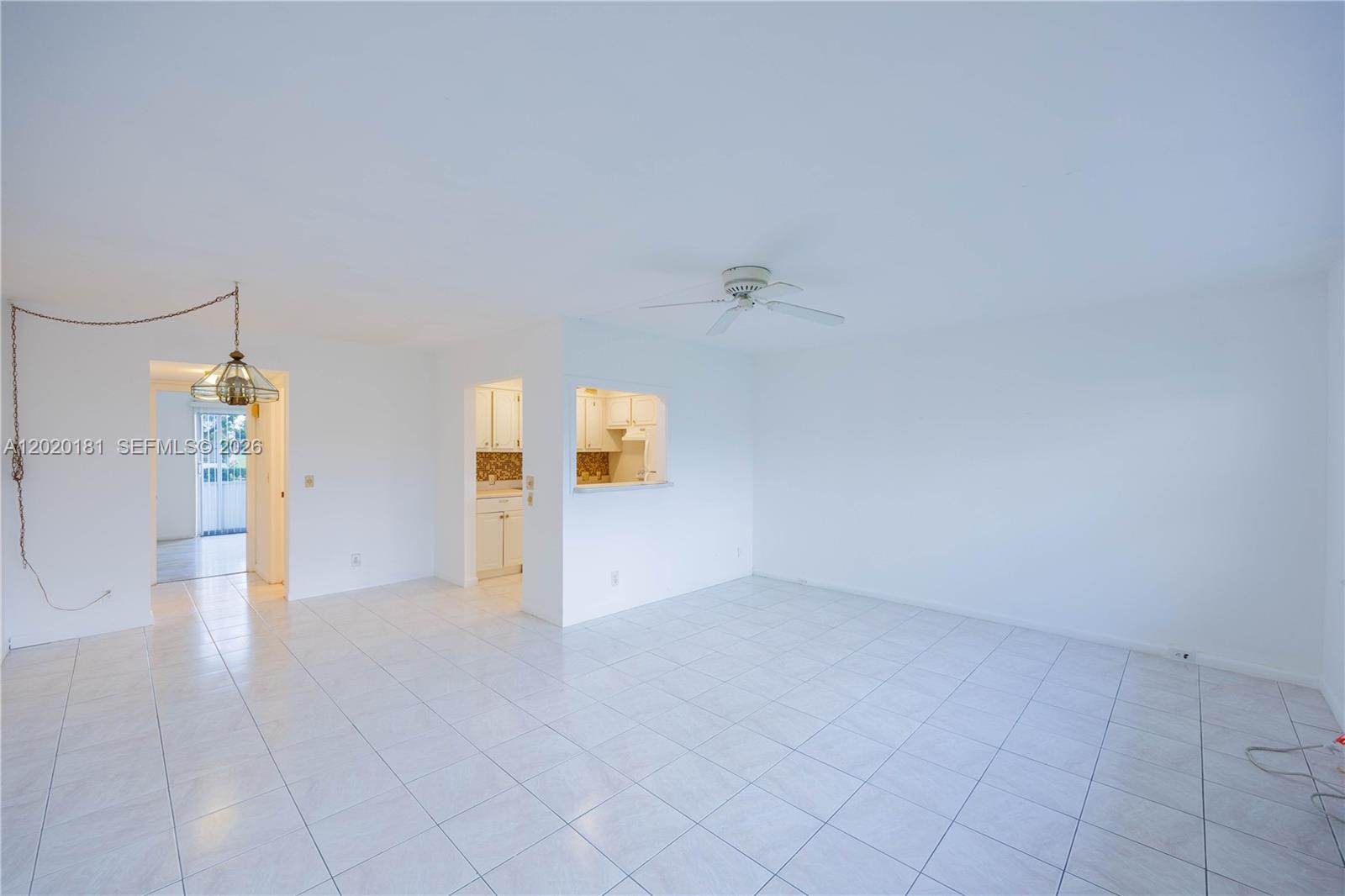A bright, tiled living room features a ceiling fan and a pass-through kitchen window — 303 Preston H # 303, Boca Raton FL 33434, BOCA RATON, FL