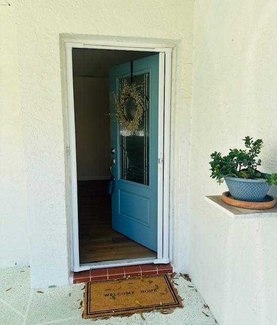 A blue front door with a wreath stands open to a room with wood flooring — 2033 HAWKHURST CIRCLE UNIT 180, SUN CITY CENTER, FL
