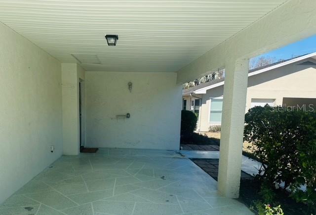 A covered concrete patio features a light-colored ceiling and a view of a neighboring house — 2033 HAWKHURST CIRCLE UNIT 180, SUN CITY CENTER, FL