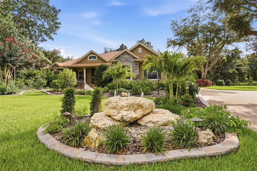 A single-story house with stone accents, a paved driveway, and illuminated landscaping at dusk — 2920 CHICKASAW CIRCLE, HAINES CITY, FL