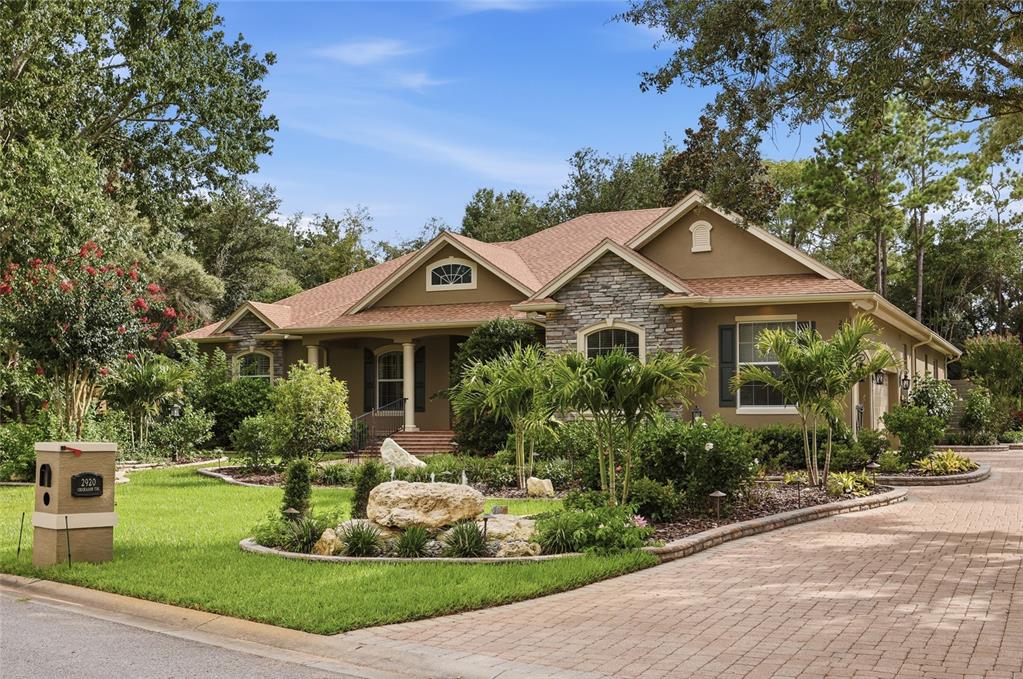 A single-story house with stone accents, a landscaped front yard, and a sunset sky — 2920 CHICKASAW CIRCLE, HAINES CITY, FL