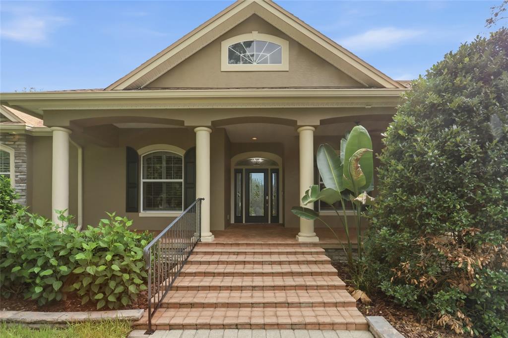 A screened-in pool patio features a kidney-shaped pool, stone-look pavers, and integrated landscape lighting — 2920 CHICKASAW CIRCLE, HAINES CITY, FL