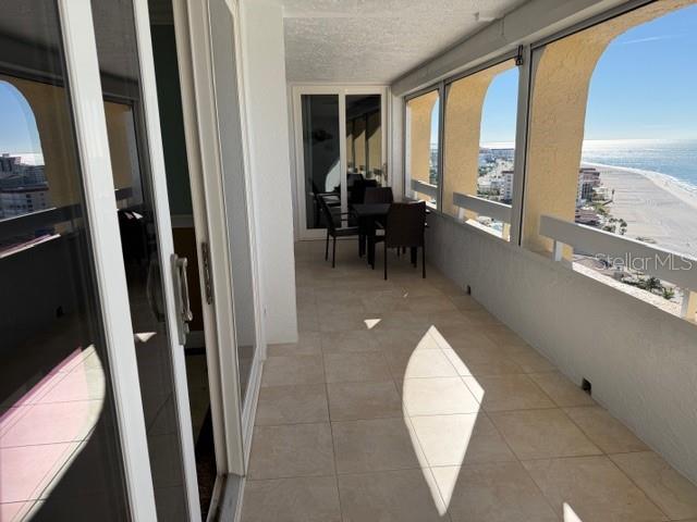 A tiled balcony features a small dining set and expansive views of the beach and ocean — 17900 GULF BOULEVARD UNIT 18C, ST PETERSBURG, FL