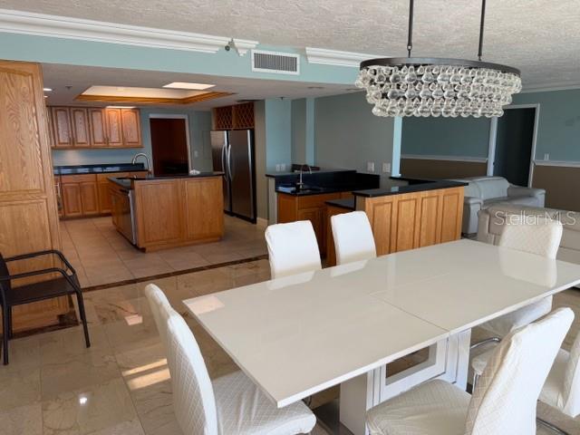 A dining area with a white table and chairs sits before an open-concept kitchen — 17900 GULF BOULEVARD UNIT 18C, ST PETERSBURG, FL