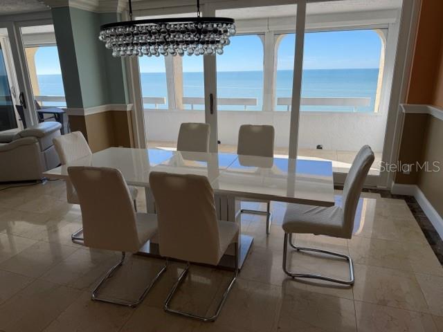 A dining room with a white table, six chairs, and a chandelier overlooking the ocean — 17900 GULF BOULEVARD UNIT 18C, ST PETERSBURG, FL