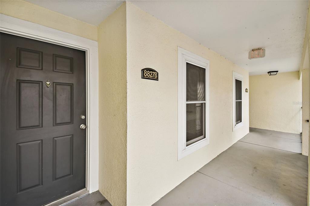 A dark front door and two windows are visible along a covered exterior walkway — 8827 GRAND PALMS CIRCLE UNIT B, KISSIMMEE, FL