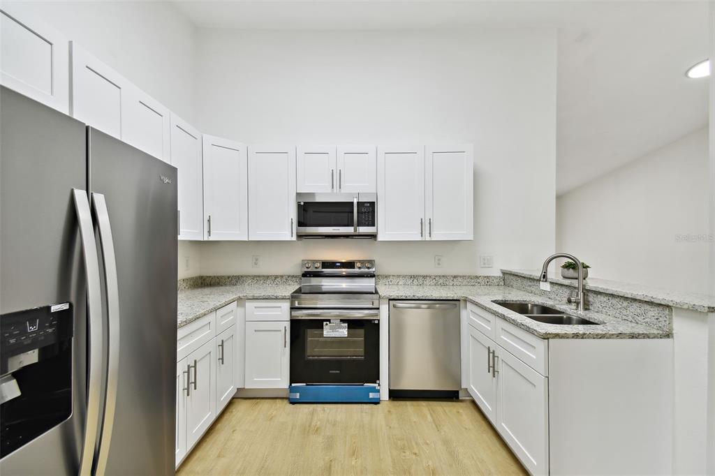 A kitchen with white cabinets, stainless steel appliances, and granite countertops — 8827 GRAND PALMS CIRCLE UNIT B, KISSIMMEE, FL