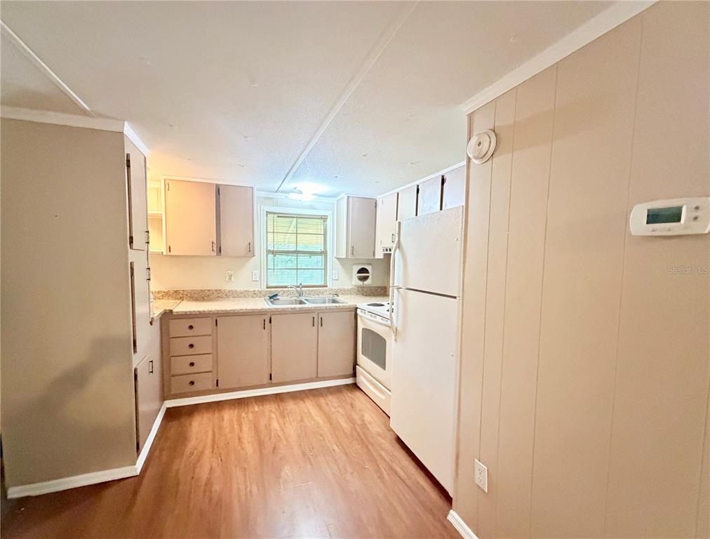 A kitchen features light-colored wood cabinets, white appliances, a window, and wood-look flooring — 141 ROBINHOOD DRIVE, DELAND, FL