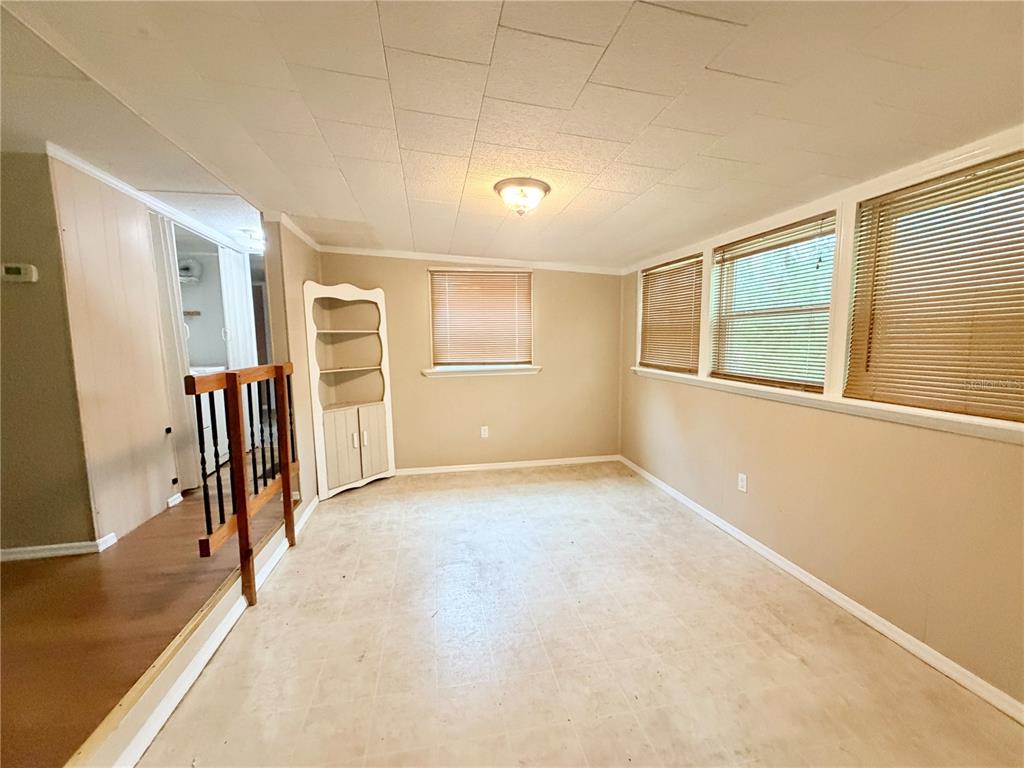 A room with beige walls, a white corner cabinet, and windows covered by horizontal blinds — 141 ROBINHOOD DRIVE, DELAND, FL