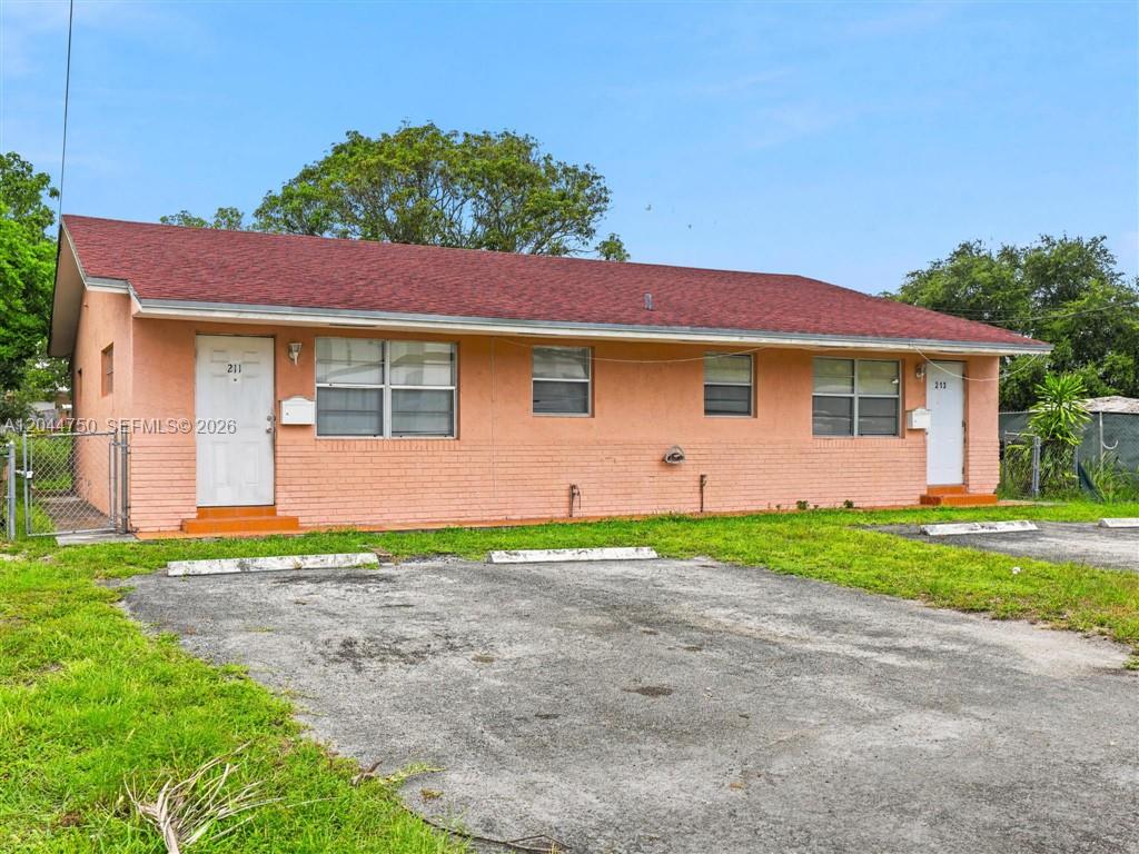 A single-story peach-colored duplex with a red shingled roof and a paved parking area — 211 SE 10th St, Hallandale Beach FL 33009, HALLANDALE BEACH, FL