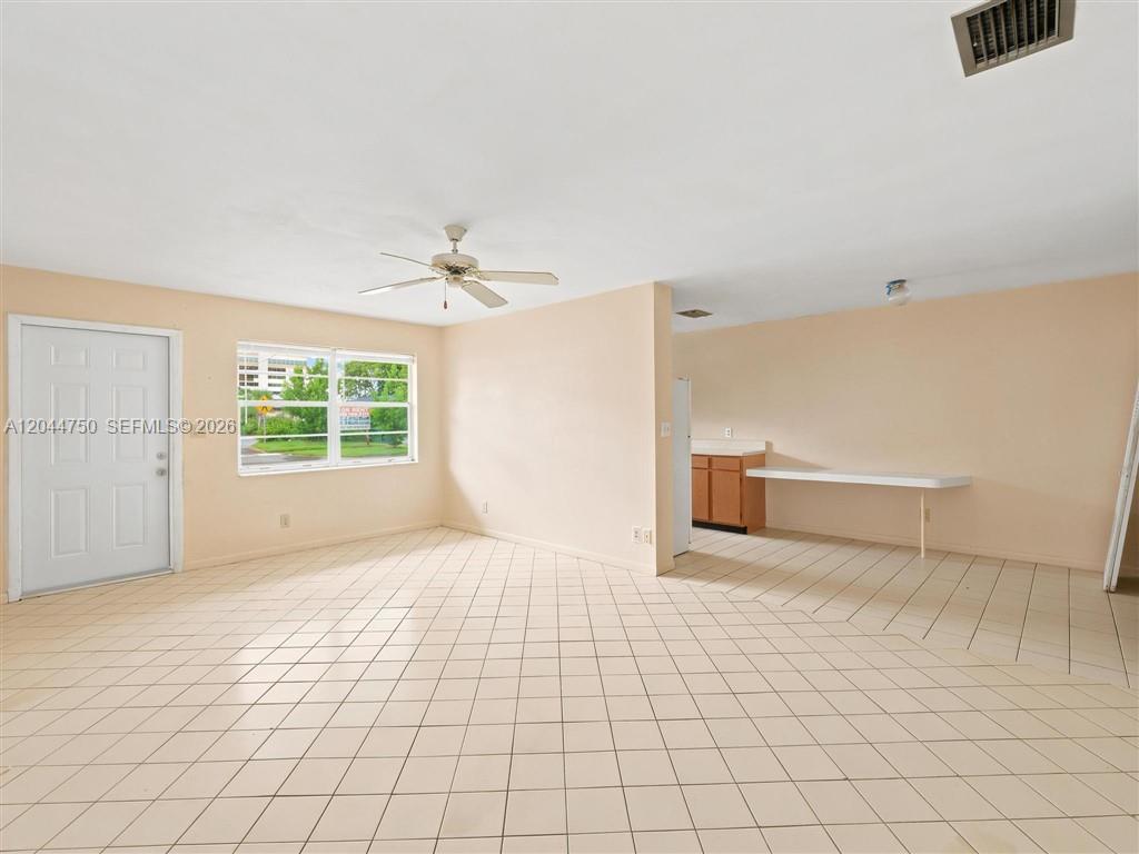 An open-concept living area features light-colored tile flooring, a ceiling fan, and a kitchen pass-through — 211 SE 10th St, Hallandale Beach FL 33009, HALLANDALE BEACH, FL