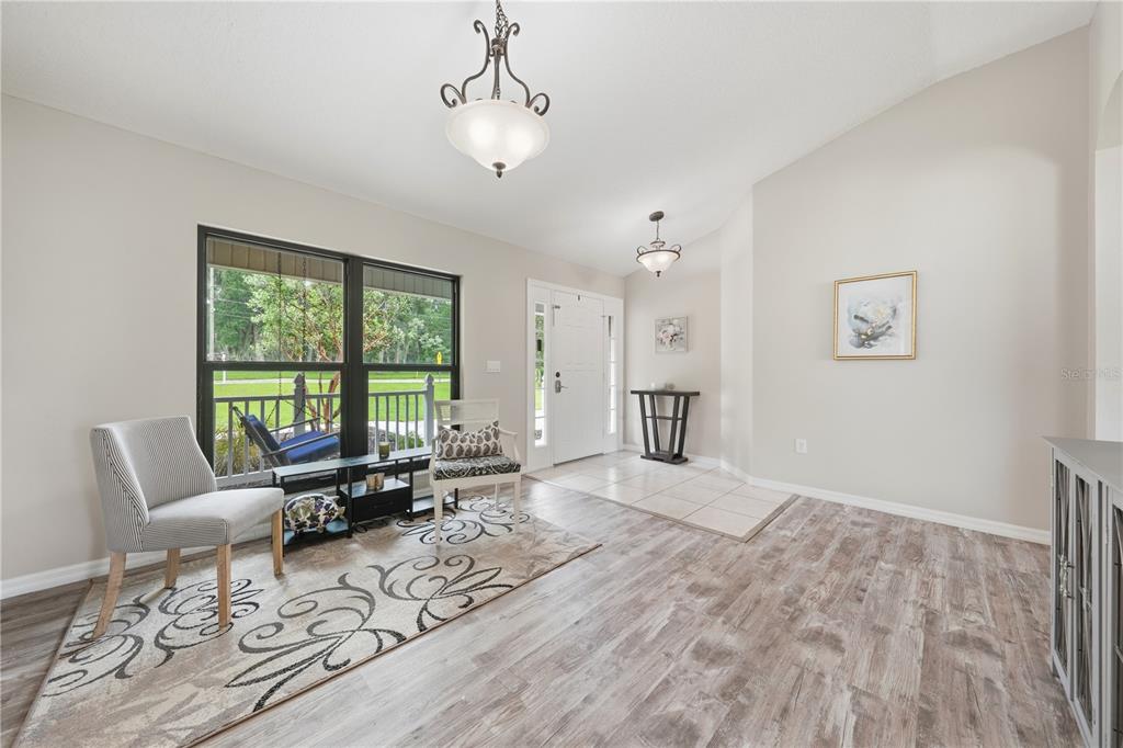 An entryway with light wood-look flooring, a patterned area rug, two chairs, and two chandeliers — 535 E PLYMOUTH AVENUE, DELAND, FL