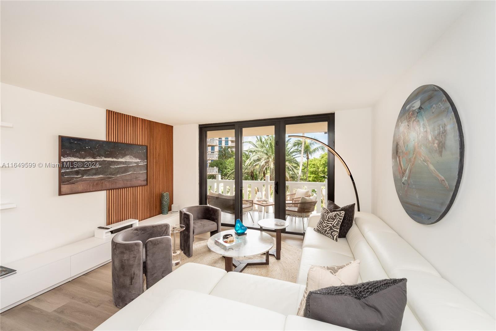 A living room features a white sectional sofa, two grey armchairs, and a wood-slatted wall — 1111 Crandon Blvd # A306, Key Biscayne FL 33149, KEY BISCAYNE, FL