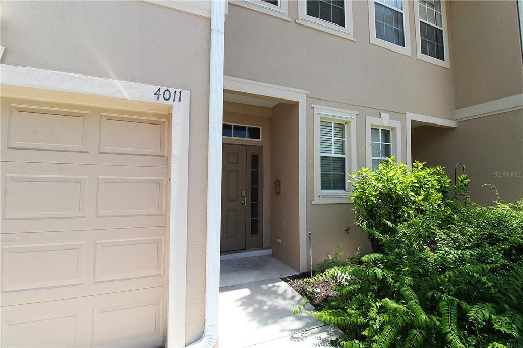 The exterior of a two-story townhouse features a garage, a front entrance, and landscaping — 4011 BURLWOOD ROAD, SARASOTA, FL