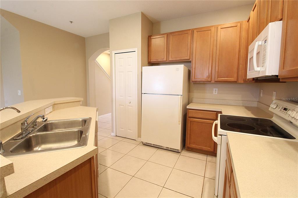 A kitchen features light-colored countertops, wood cabinets, white appliances, and a double-basin sink — 4011 BURLWOOD ROAD, SARASOTA, FL