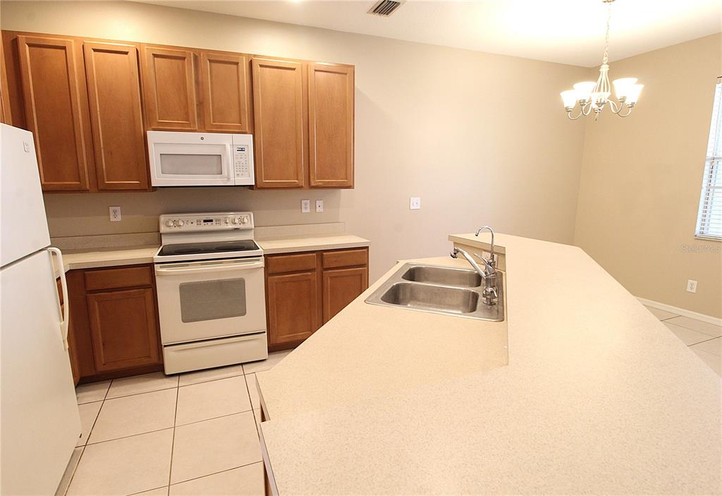 A kitchen features wood cabinets, white appliances, a double sink, and a breakfast bar — 4011 BURLWOOD ROAD, SARASOTA, FL
